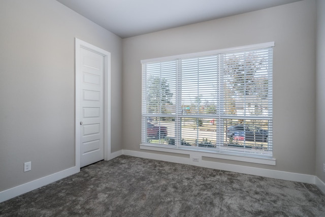 empty room with baseboards and dark carpet