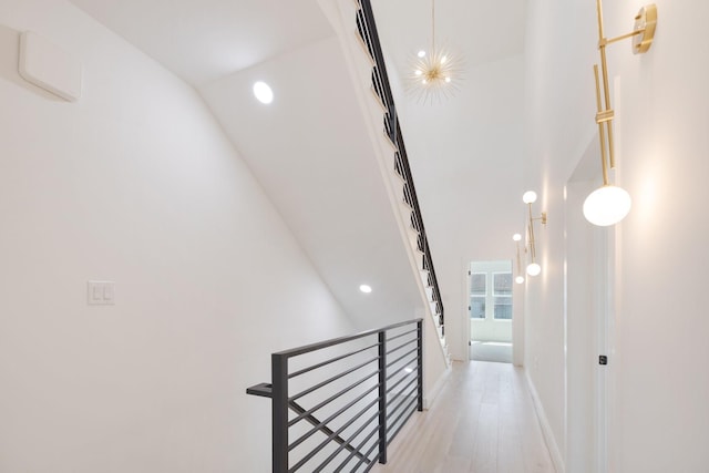 hallway with recessed lighting, light wood-style floors, baseboards, and an upstairs landing