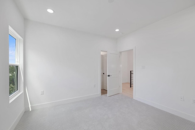empty room with light colored carpet, baseboards, and plenty of natural light
