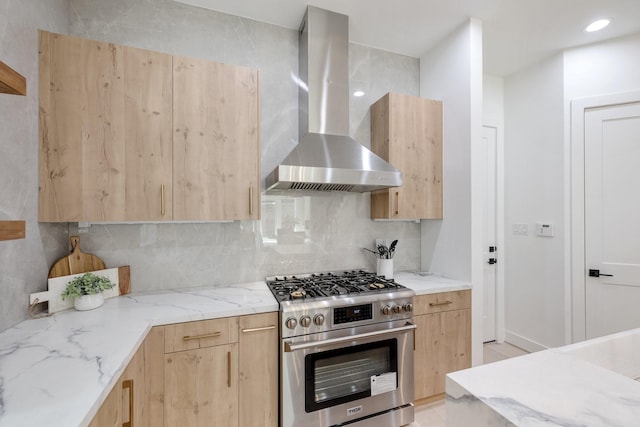 kitchen with wall chimney exhaust hood, high end range, backsplash, and light brown cabinetry