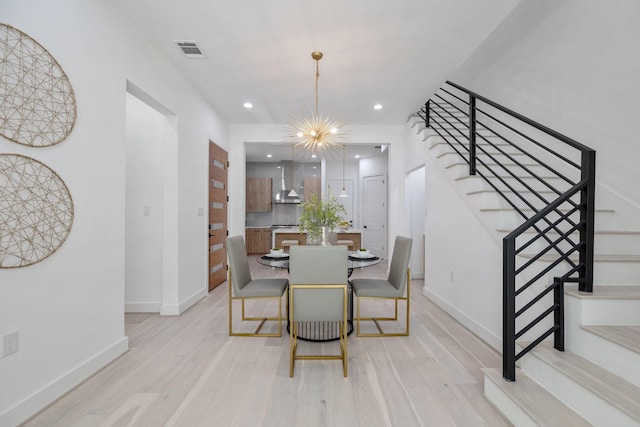 dining area featuring stairway, light wood finished floors, visible vents, baseboards, and a notable chandelier