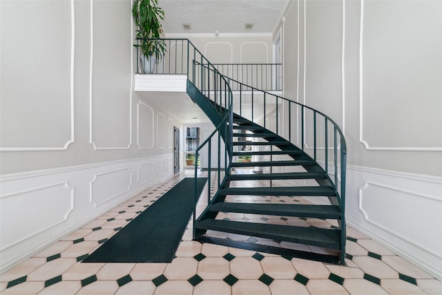 3400 Timmons Ln Unit 68, Houston, TX 77027 - stairs with a decorative wall, crown molding, tile patterned floors, and wainscoting