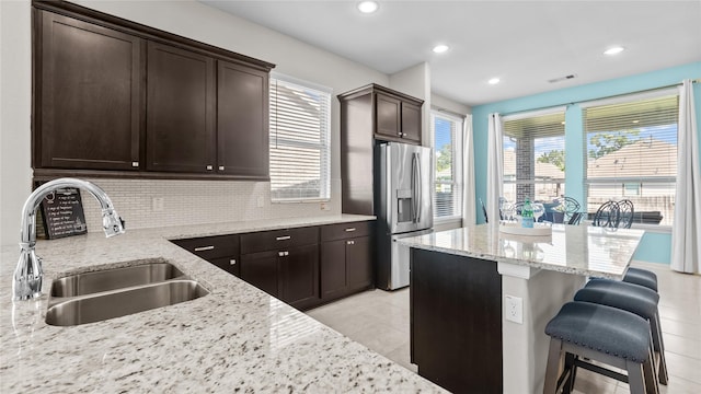 119 Buckeye Dr, Montgomery, TX 77316 - kitchen with a sink, a kitchen breakfast bar, visible vents, stainless steel fridge with ice dispenser, and dark brown cabinets