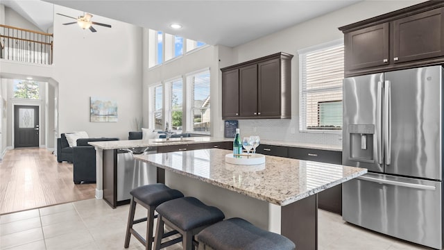 119 Buckeye Dr, Montgomery, TX 77316 - kitchen featuring stainless steel appliances, ceiling fan, a center island, light stone countertops, and dark brown cabinets