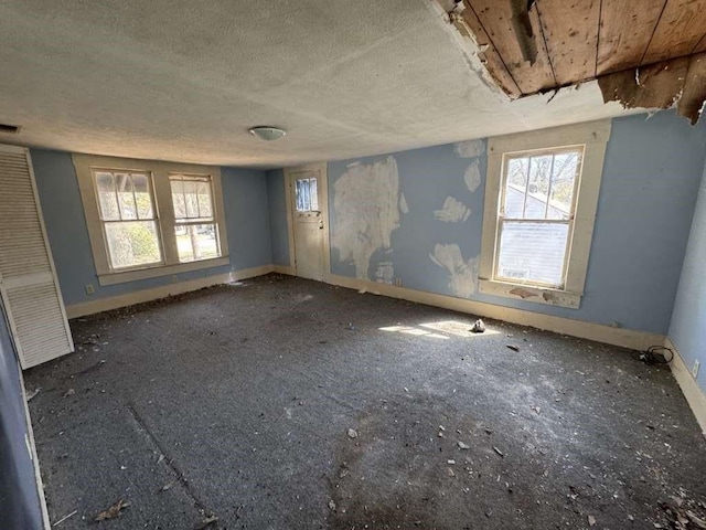 unfurnished room featuring baseboards and a textured ceiling