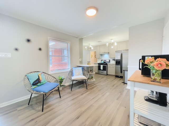 interior space with baseboards, a notable chandelier, and light wood finished floors