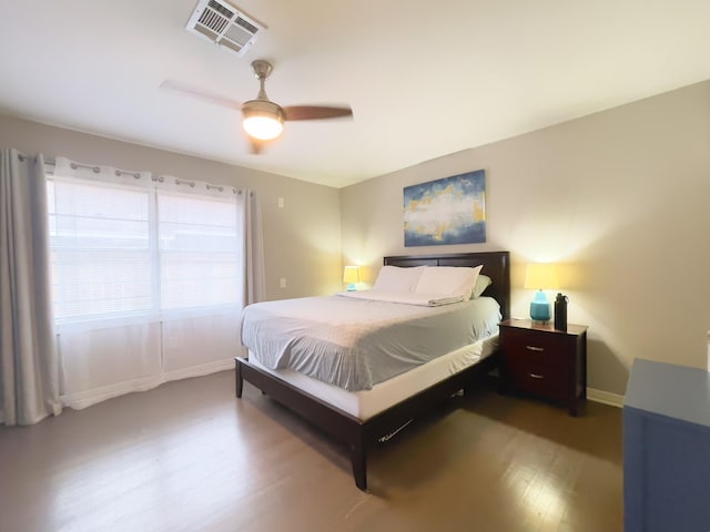 bedroom with wood finished floors, visible vents, a ceiling fan, and baseboards