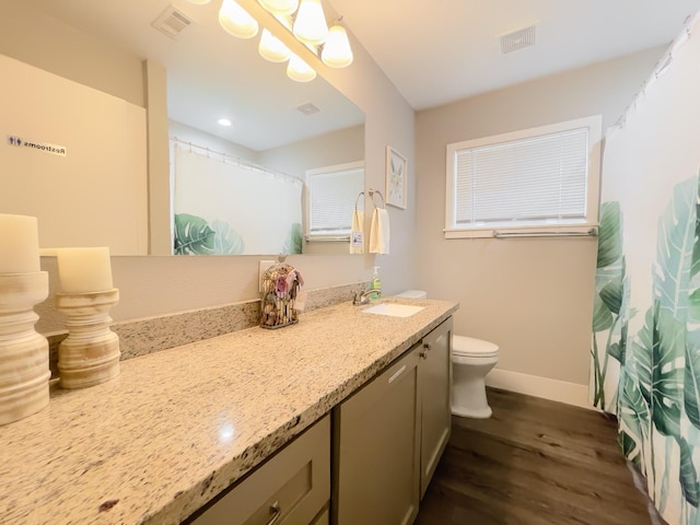 full bath featuring toilet, vanity, wood finished floors, and visible vents