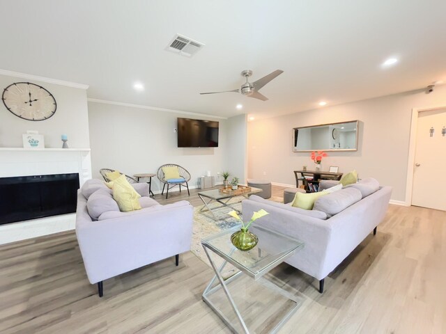 living area featuring a fireplace, light wood-type flooring, visible vents, and recessed lighting