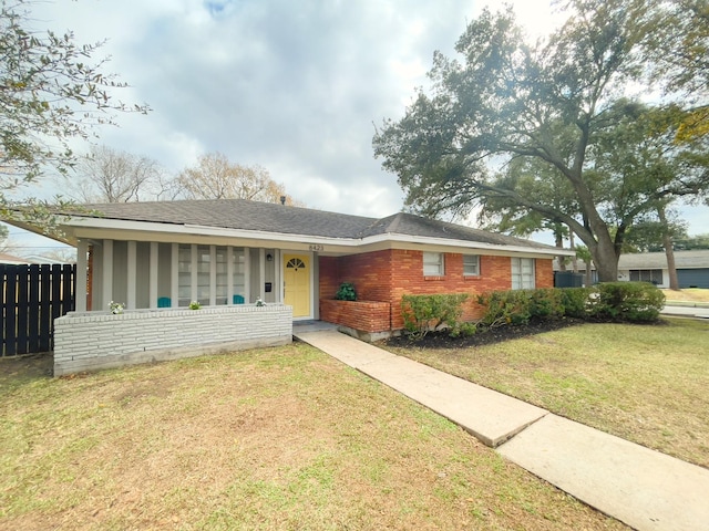 ranch-style home with brick siding, a front lawn, and fence