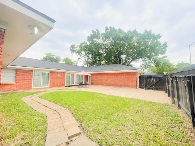 back of property with brick siding, a patio area, a lawn, and fence