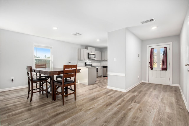 dining space with light wood-type flooring, baseboards, and visible vents