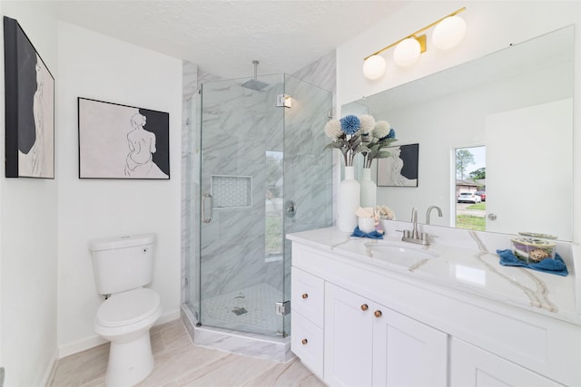 full bath featuring toilet, vanity, a marble finish shower, baseboards, and a textured ceiling