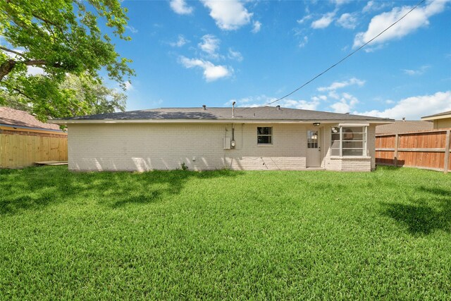 back of house with a lawn, a fenced backyard, brick siding, and a sunroom