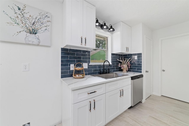 kitchen featuring dishwasher, decorative backsplash, white cabinetry, and a sink