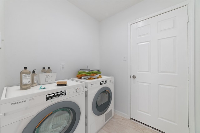 clothes washing area featuring separate washer and dryer and laundry area