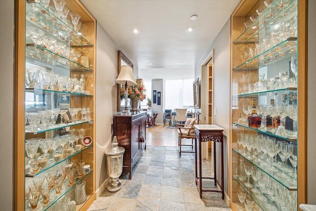bar with a bar, recessed lighting, baseboards, and stone tile flooring