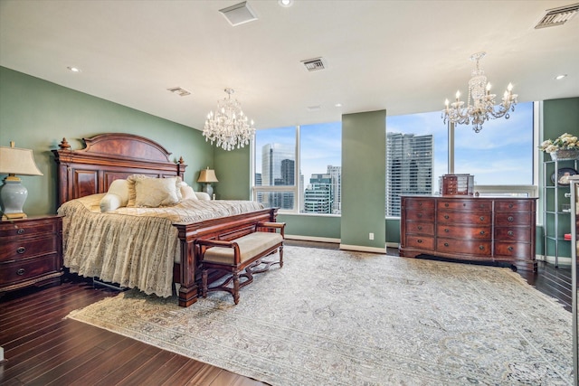 bedroom with an inviting chandelier, a city view, wood finished floors, and visible vents