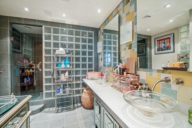 full bathroom with recessed lighting, double vanity, tiled shower, and tile walls