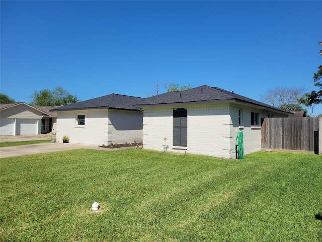 view of front of property featuring brick siding, fence, a shingled roof, and a front yard