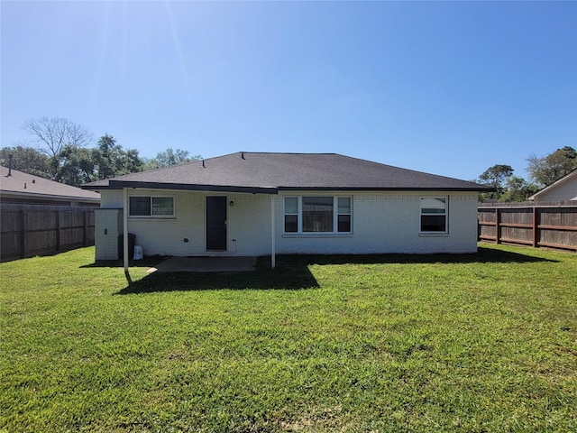 rear view of house featuring a yard, brick siding, a fenced backyard, and a patio area