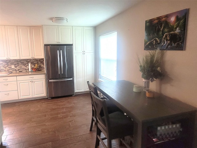 kitchen featuring freestanding refrigerator, backsplash, dark wood finished floors, and white cabinetry