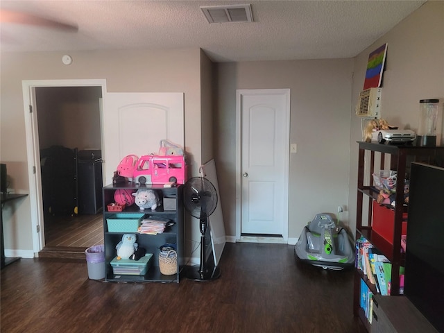 misc room featuring visible vents, baseboards, a textured ceiling, and wood finished floors