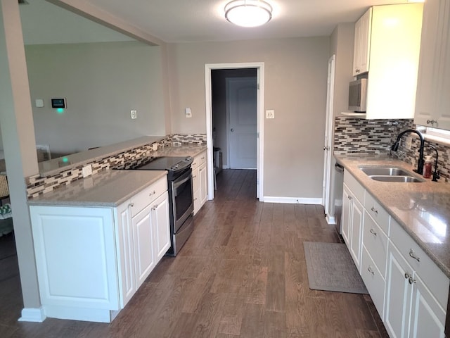 kitchen with a sink, stainless steel appliances, white cabinetry, tasteful backsplash, and dark wood-style floors