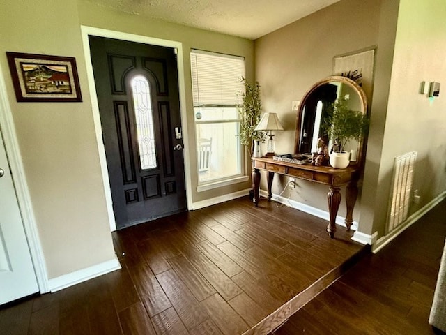 foyer featuring baseboards, visible vents, and wood finished floors