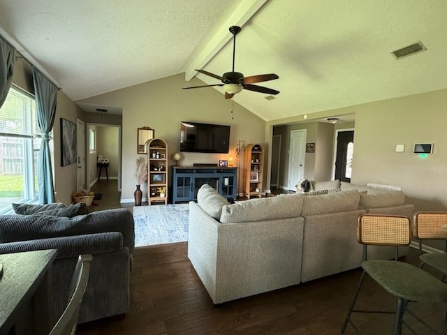 living area featuring visible vents, lofted ceiling with beams, a textured ceiling, a ceiling fan, and dark wood finished floors