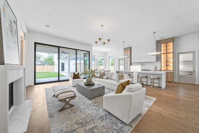 216 W 31st St, Houston, TX 77018 - living room with light wood-style flooring, a chandelier, a fireplace, and recessed lighting