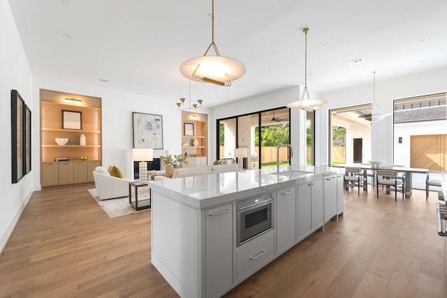 216 W 31st St, Houston, TX 77018 - kitchen with a sink, light wood-style floors, a spacious island, light stone countertops, and pendant lighting