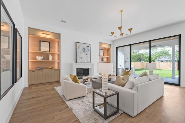 216 W 31st St, Houston, TX 77018 - living room featuring a glass covered fireplace, light wood-style flooring, a chandelier, and built in shelves