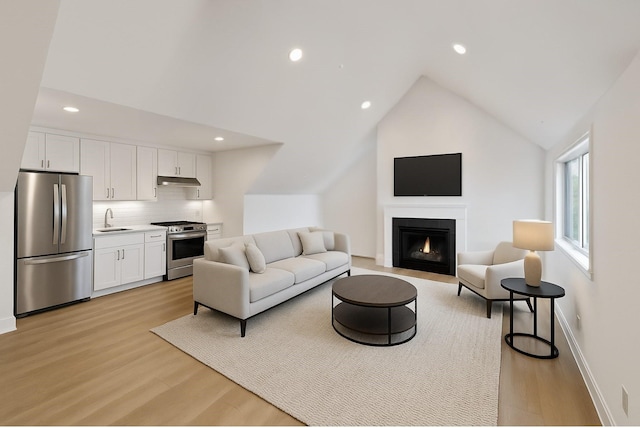 216 W 31st St, Houston, TX 77018 - living area featuring light wood finished floors, recessed lighting, lofted ceiling, a fireplace with flush hearth, and baseboards
