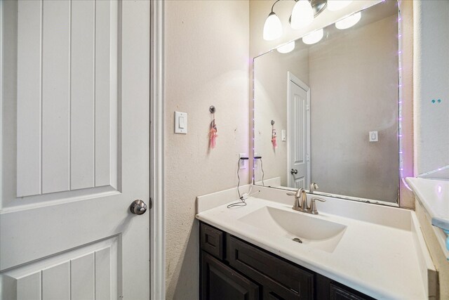 bathroom with a textured wall and vanity