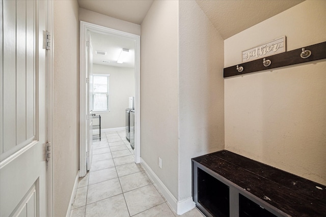 mudroom with light tile patterned flooring, visible vents, washing machine and clothes dryer, and baseboards
