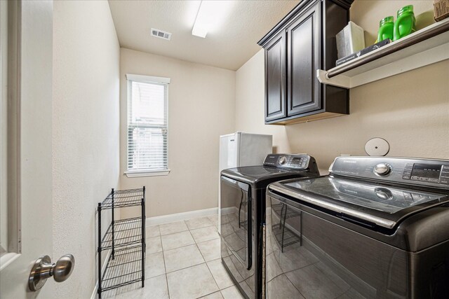 laundry area featuring baseboards, visible vents, cabinet space, washer and dryer, and light tile patterned floors