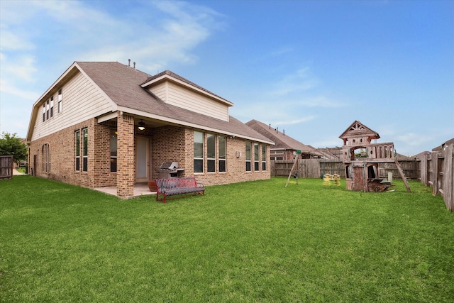 rear view of property with brick siding, a patio area, a fenced backyard, and a playground