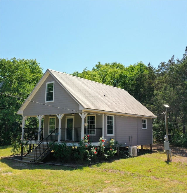 rear view of property featuring ac unit, covered porch, a yard, and metal roof