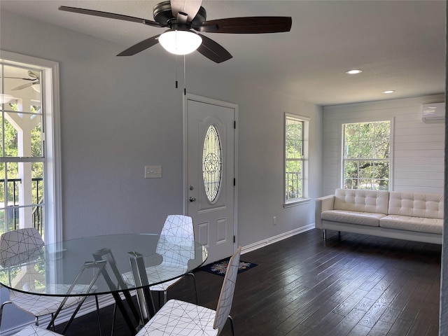 dining room with an AC wall unit, dark wood-style flooring, a ceiling fan, and baseboards