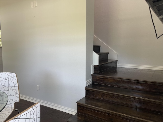 staircase featuring wood finished floors and baseboards