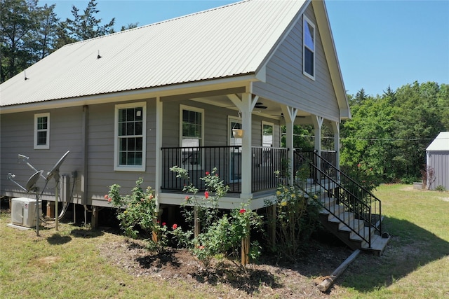 rear view of house with stairway, a lawn, a porch, and metal roof