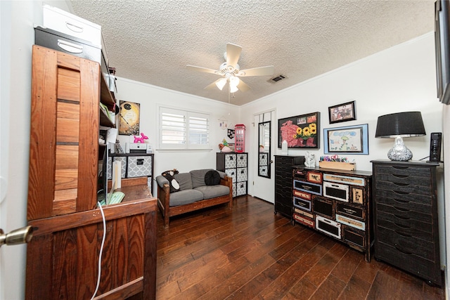 living area featuring dark wood-type flooring, a textured ceiling, a ceiling fan, and ornamental molding