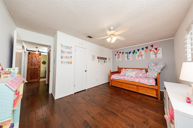 bedroom with a textured ceiling, hardwood / wood-style floors, visible vents, and ornamental molding