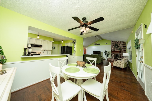 dining space with a ceiling fan, a textured ceiling, hardwood / wood-style flooring, a fireplace, and visible vents