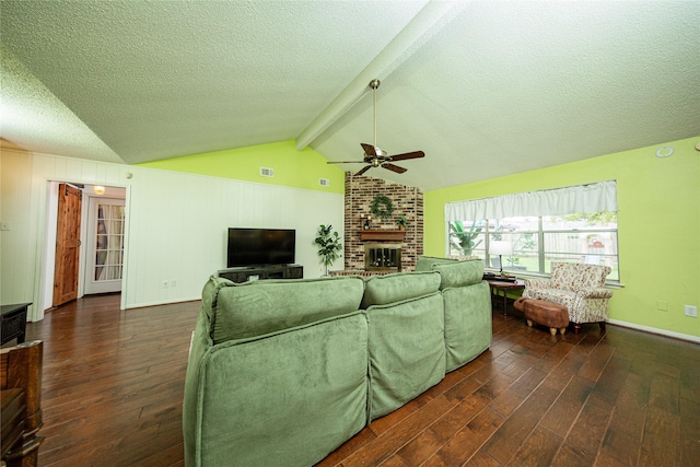 living room featuring a ceiling fan, wood finished floors, a textured ceiling, vaulted ceiling with beams, and a brick fireplace