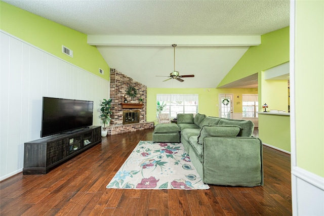 living area featuring vaulted ceiling with beams, visible vents, ceiling fan, hardwood / wood-style flooring, and a fireplace