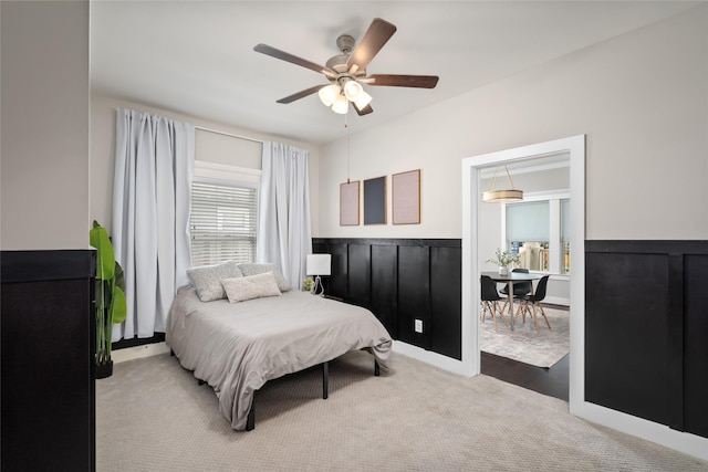 bedroom featuring carpet floors, wainscoting, and ceiling fan