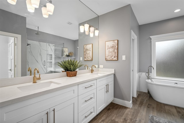 full bath featuring a sink, a stall shower, double vanity, and wood finished floors