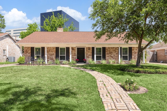 single story home featuring a porch, a chimney, a front yard, brick siding, and central AC